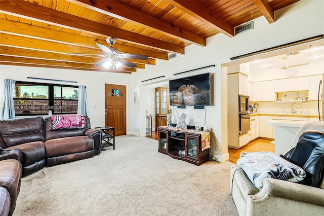 living area with visible vents, beamed ceiling, light carpet, wooden ceiling, and a ceiling fan