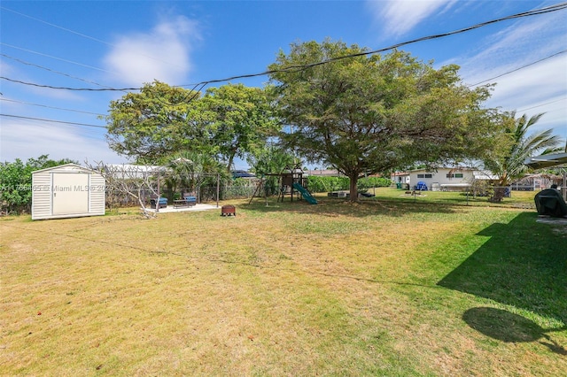 view of yard with an outbuilding, a storage shed, a playground, and a fenced backyard