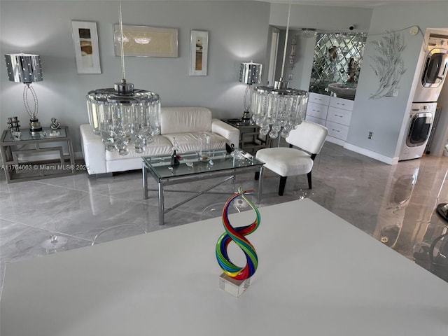living area with stacked washing maching and dryer and marble finish floor