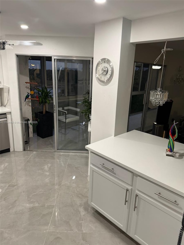 kitchen featuring white cabinets, light countertops, stainless steel dishwasher, and marble finish floor