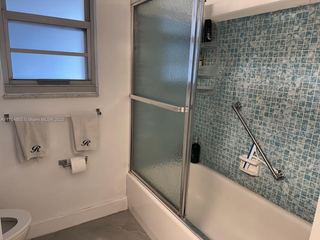 bathroom featuring toilet, baseboards, and bath / shower combo with glass door