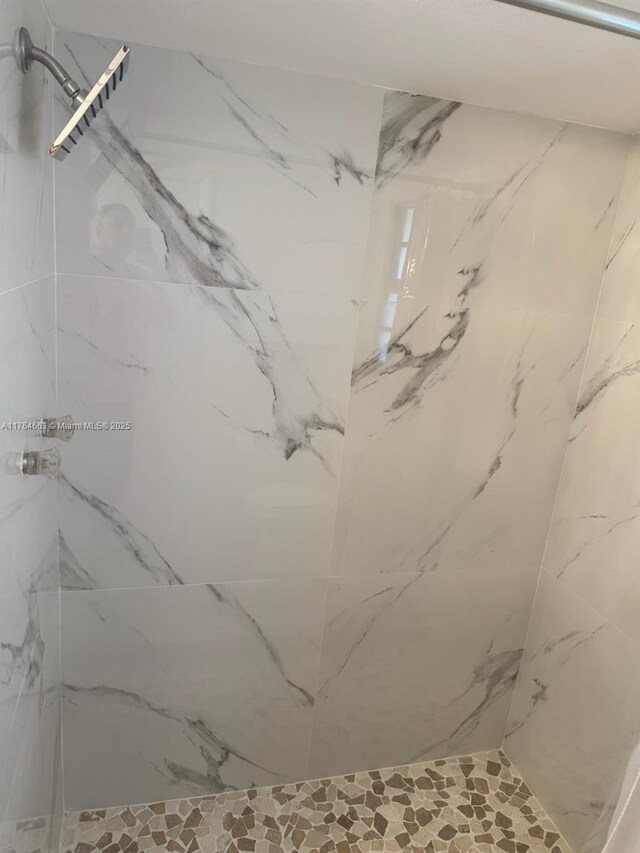 bathroom featuring a marble finish shower