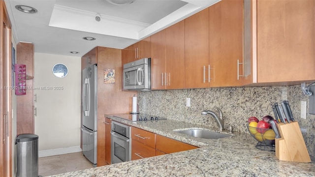 kitchen featuring light stone counters, brown cabinets, appliances with stainless steel finishes, and a sink