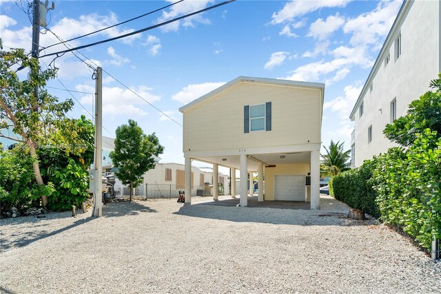 view of front of home with a carport, gravel driveway, a garage, and fence