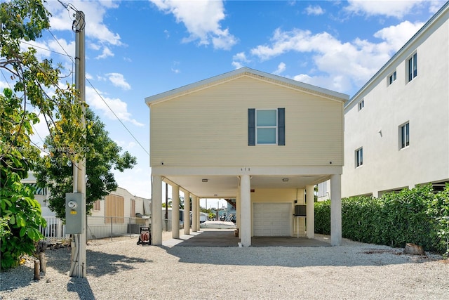 view of front of home featuring a carport, gravel driveway, and fence