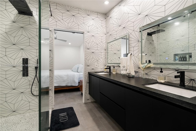 ensuite bathroom featuring tile walls, a stall shower, and a sink