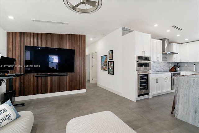 kitchen with decorative backsplash, beverage cooler, wall chimney exhaust hood, and white cabinets