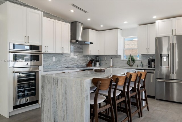 kitchen featuring light stone countertops, visible vents, wine cooler, appliances with stainless steel finishes, and wall chimney exhaust hood