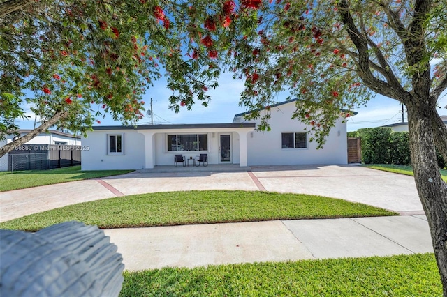 single story home featuring stucco siding, a patio area, a front lawn, and fence
