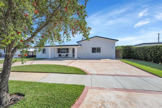 ranch-style house featuring stucco siding, concrete driveway, a front lawn, and fence