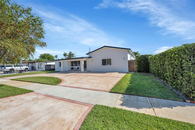single story home featuring stucco siding, fence, concrete driveway, a front yard, and a patio area