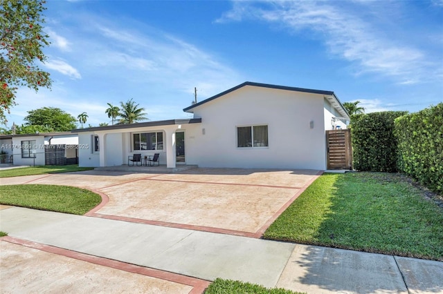 ranch-style house featuring a patio, a front lawn, driveway, and stucco siding