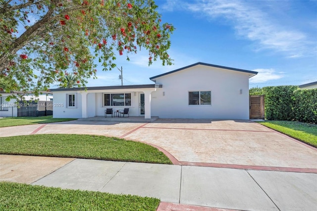 ranch-style house featuring stucco siding, concrete driveway, a front yard, and fence