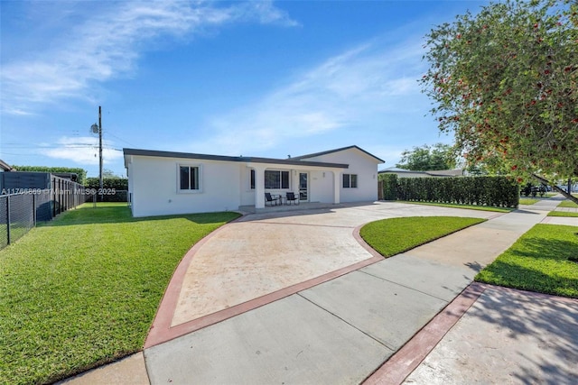view of front facade featuring a patio, fence, driveway, stucco siding, and a front lawn