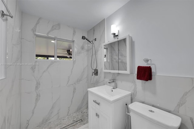 full bath with a marble finish shower, toilet, tile walls, and vanity
