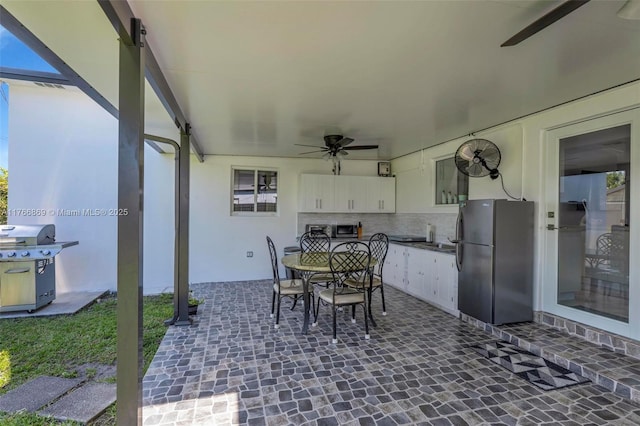 view of patio / terrace featuring grilling area, outdoor dining area, ceiling fan, and area for grilling