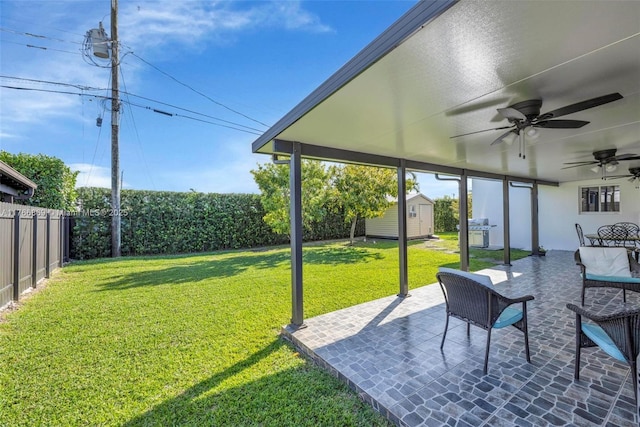 view of yard with a patio, a ceiling fan, a fenced backyard, an outdoor structure, and a storage shed