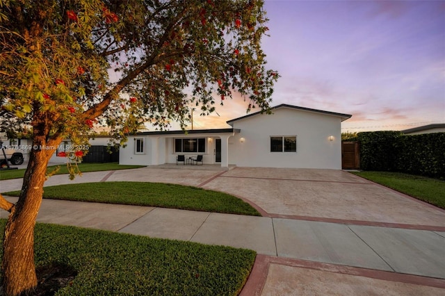 single story home featuring a patio area, a lawn, fence, and stucco siding
