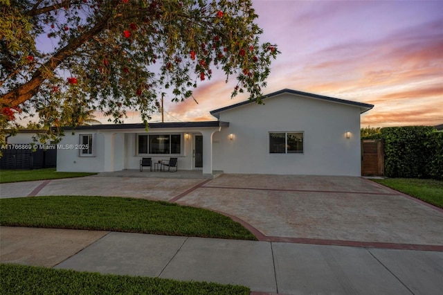 single story home featuring stucco siding, a patio, and a front lawn