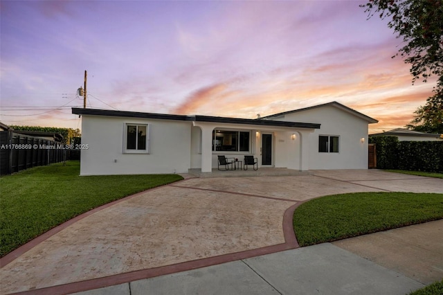 single story home featuring stucco siding, a patio, a front yard, and fence