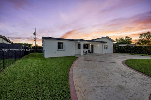 view of front of house featuring a front lawn, fence private yard, driveway, and stucco siding