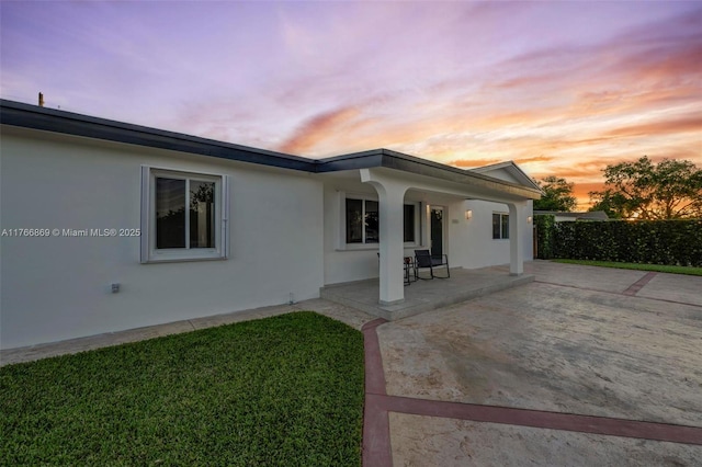 back of house at dusk featuring a patio area and stucco siding