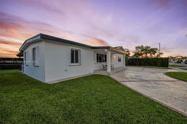 view of front of property featuring a front lawn, stucco siding, fence, and a patio
