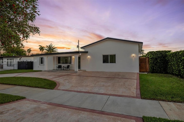 single story home featuring a patio, concrete driveway, a front lawn, and stucco siding