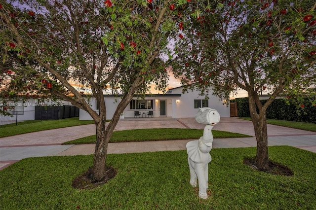 view of front of home featuring stucco siding, concrete driveway, a front lawn, and fence