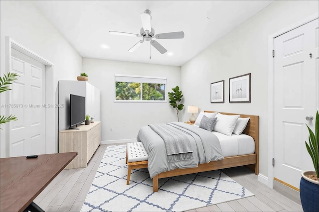 bedroom with a ceiling fan, baseboards, and light wood-style floors