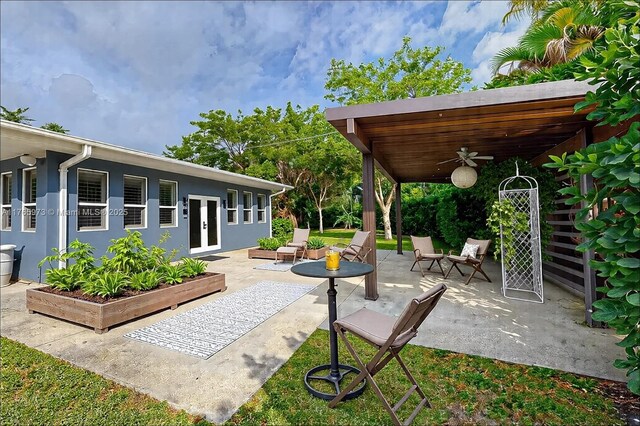 view of patio with ceiling fan, a garden, and french doors