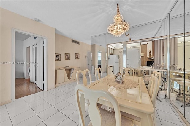 dining space with an inviting chandelier, light tile patterned floors, and visible vents
