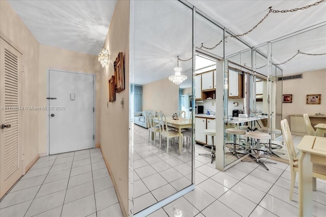 interior space with light tile patterned floors, visible vents, and an inviting chandelier