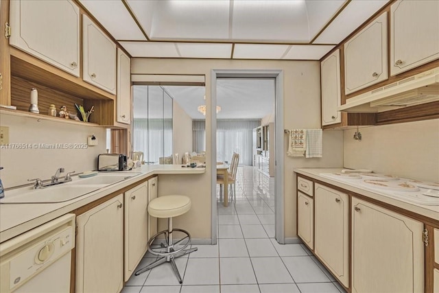 kitchen featuring under cabinet range hood, light countertops, light tile patterned floors, white appliances, and a sink