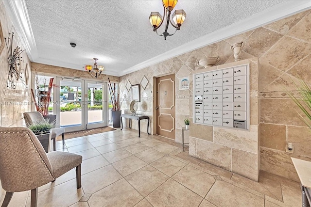 entryway with french doors, a textured ceiling, an inviting chandelier, and ornamental molding