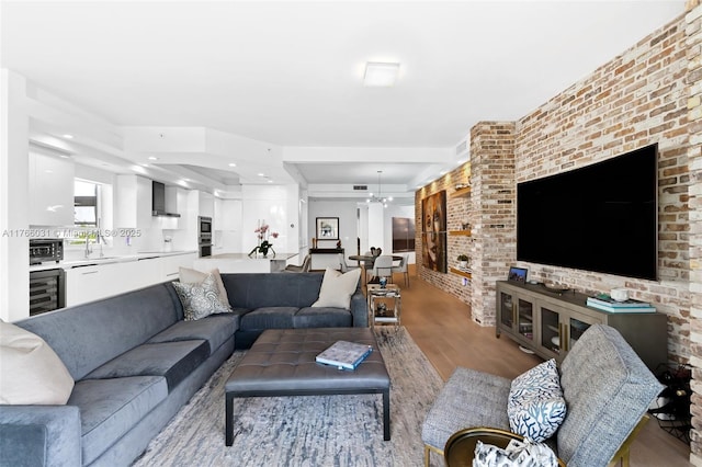 living room featuring wine cooler, a toaster, light wood-style floors, and brick wall