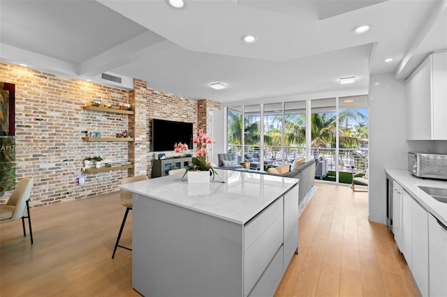 kitchen featuring white cabinetry, brick wall, modern cabinets, and a wall of windows