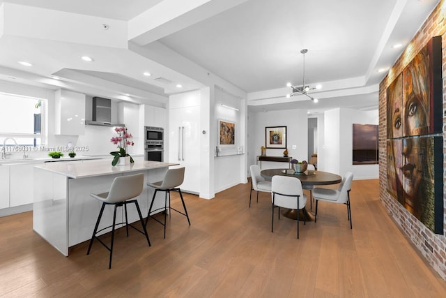 kitchen with modern cabinets, wall chimney exhaust hood, white cabinets, and light countertops