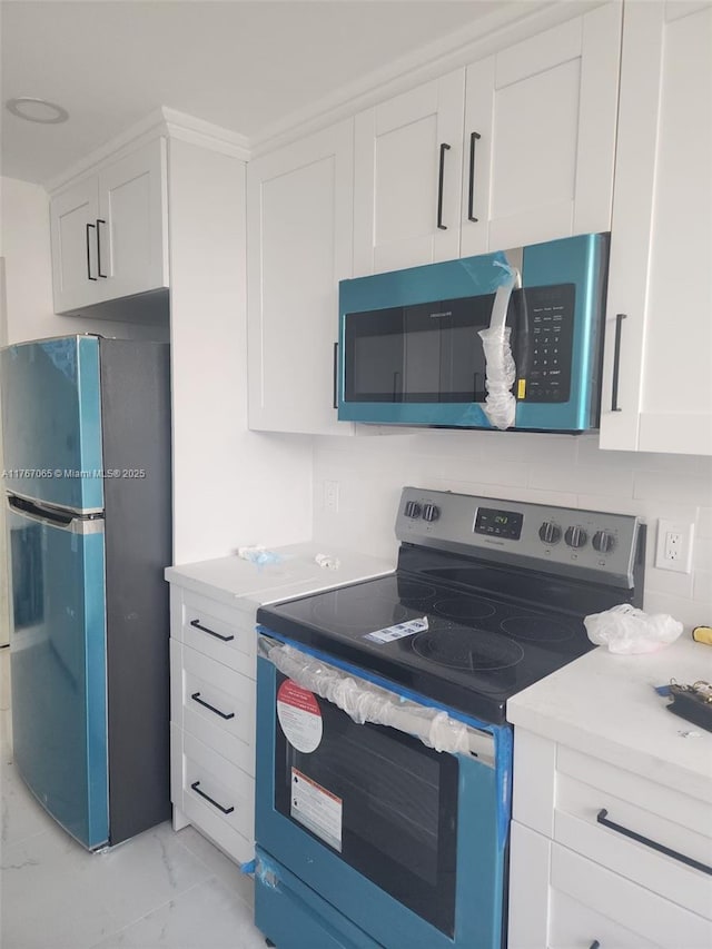 kitchen featuring stainless steel appliances, marble finish floor, light countertops, and white cabinetry