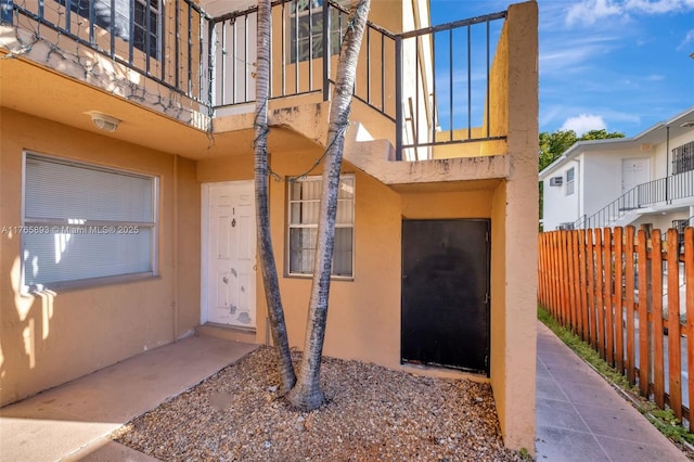 property entrance with stucco siding and fence