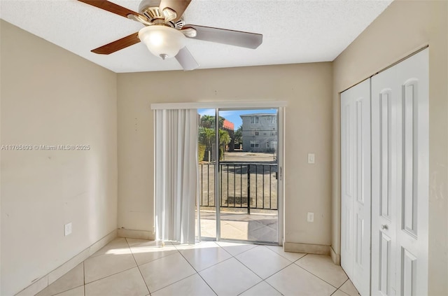 interior space with a textured ceiling, ceiling fan, baseboards, and tile patterned floors