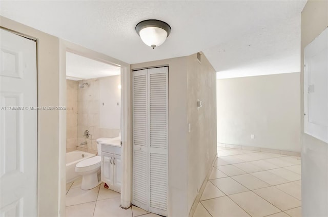 corridor featuring light tile patterned flooring, a textured ceiling, and baseboards