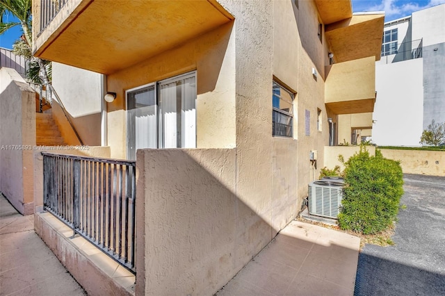 exterior space featuring stucco siding, central air condition unit, and fence