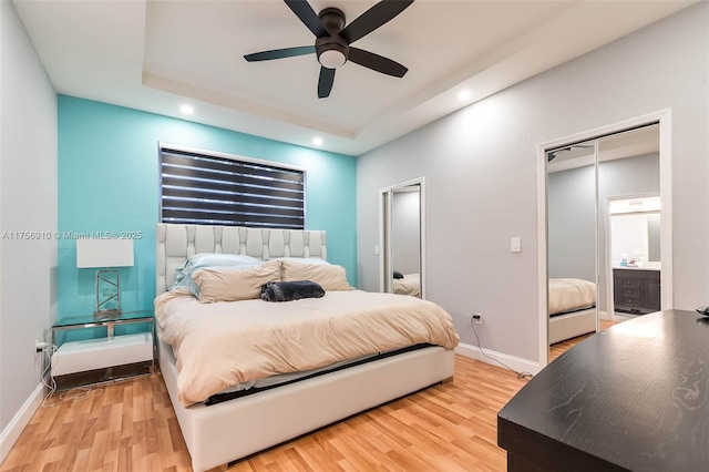 bedroom featuring a tray ceiling, recessed lighting, light wood finished floors, baseboards, and ceiling fan