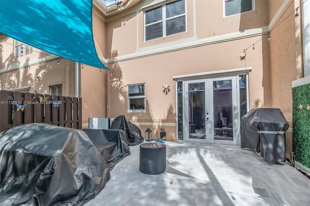 back of property with french doors, fence, stucco siding, and a patio area