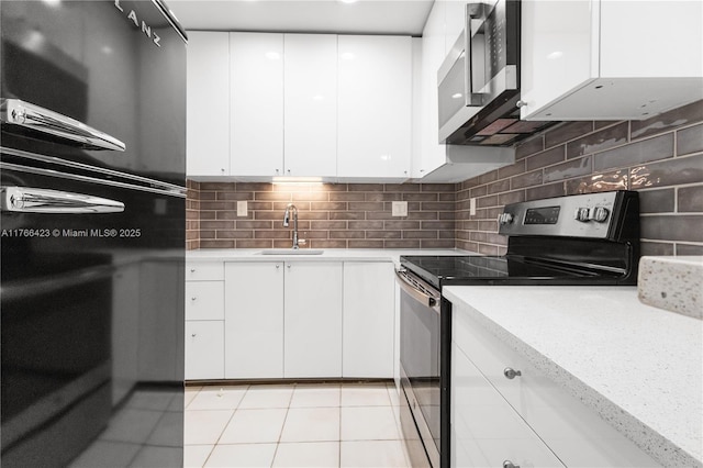 3040 NE 16th Ave Unit 104, Oakland Park, FL 33334 - kitchen featuring appliances with stainless steel finishes, a sink, light countertops, light tile patterned floors, and white cabinetry