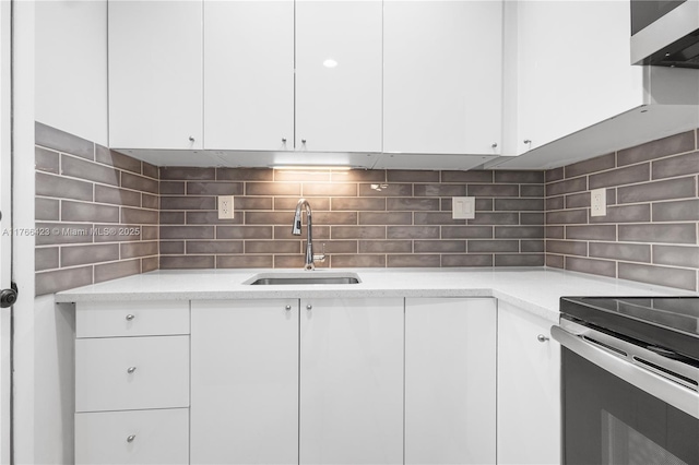 3040 NE 16th Ave Unit 104, Oakland Park, FL 33334 - kitchen with a sink, backsplash, white cabinets, and stainless steel electric range