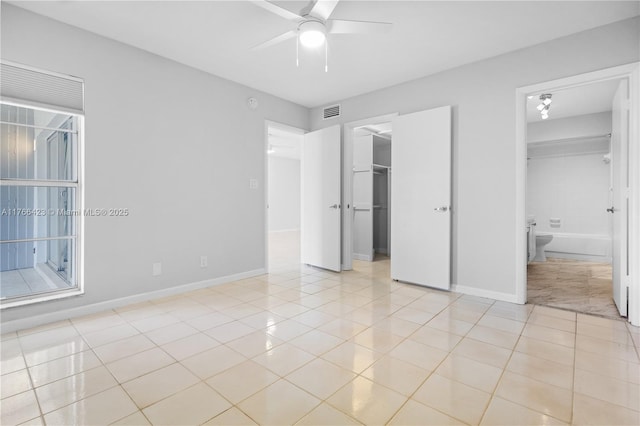 3040 NE 16th Ave Unit 104, Oakland Park, FL 33334 - unfurnished bedroom with a spacious closet, light tile patterned floors, baseboards, a closet, and a ceiling fan