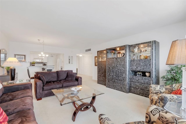 living room with visible vents, an inviting chandelier, a fireplace, and carpet