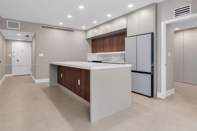 5255 Collins Ave Unit 9B, Miami Beach, FL 33140 - kitchen featuring freestanding refrigerator, modern cabinets, a center island, light countertops, and baseboards